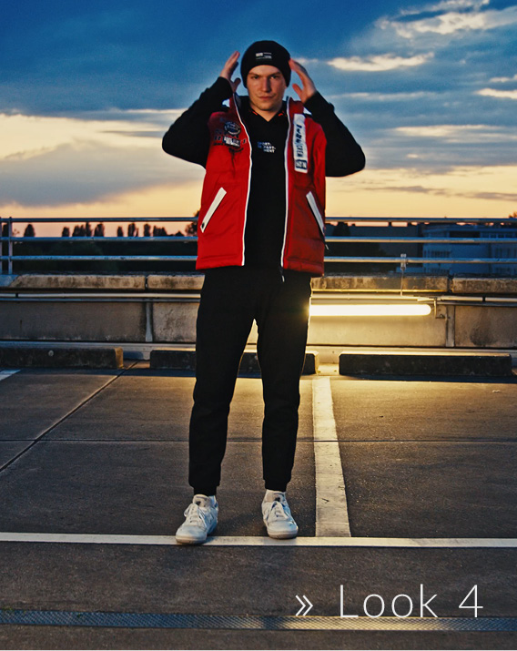 Model trägt schwarzen Hoodie und Mütze mit roter Jacke
