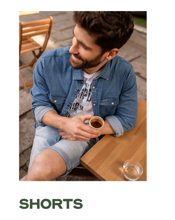 Model sitzt mit Jeanslook im Cafe.